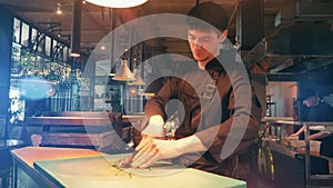 Male restaurant worker is cutting herbs