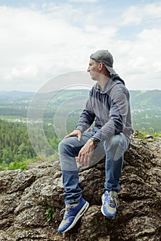 Male resting and enjoying the mountain sitting on rock