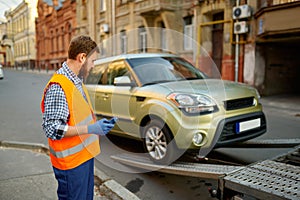 Male road worker monitoring car loading process