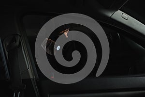 male robber in black balaclava with flashlight looking into