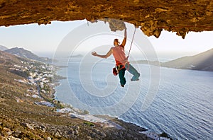 Male rock climber on challenging route going along ceiling in cave