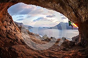 Male rock climber climbing along a roof in a cave