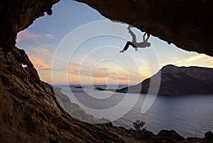 Male rock climber climbing along a roof in a cave