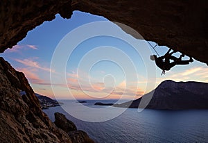 Male rock climber climbing along a roof in a cave