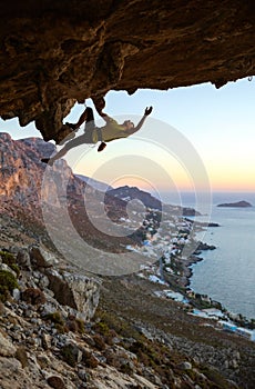 Male rock climber climbing along a roof in a cave