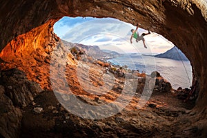 Male rock climber climbing along a roof in a cave photo