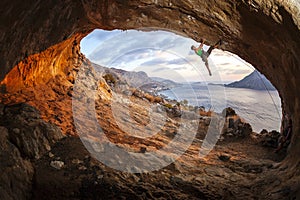 Male rock climber climbing along a roof in a cave