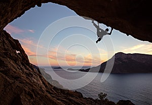 Male rock climber climbing along a roof in a cave