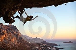 Male rock climber climbing along a roof in a cave