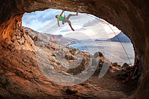 Male rock climber climbing along a roof in a cave