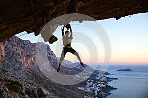 Male rock climber gripping handhold on ceiling in cave photo