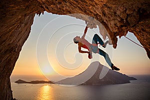 Male rock climber hanging with one hand on challenging route on cliff photo