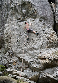 Male rock climber training rock climbing on a huge boulder