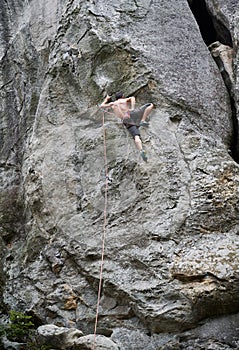 Male rock climber training rock climbing on a huge boulder