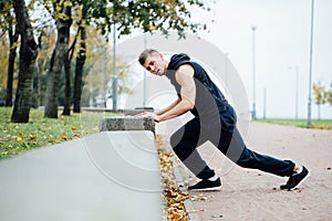 Male runner doing exercise, workout in the fall park. Push ups with bench.