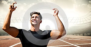 Male runner with hands in air on track against flares