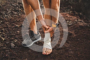 Male runner holding injured bandaging leg close-up