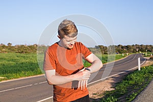 Male runner jogging outside looking at his wearable fitness tracker outside.