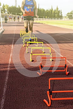 Male runner training jumping hurdles