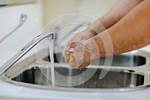 Male`s doctor`s hands washing with foam under the water stream
