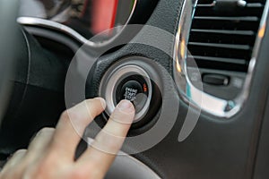 Male& x27;s finger pressing the start button, stop the engine in the luxury car