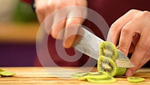 Male`s hand cutting fresh kiwi on cutting board.