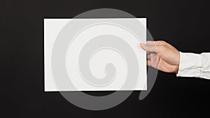 Male`s hand is holding blank A4 paper and wear white shirt  on white background.Empty space for text