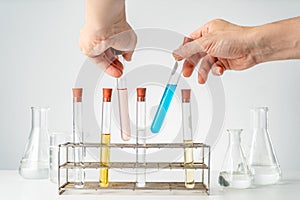 Male`s hands holding chemistry lab`s test tubes, putting them back in the tube holders