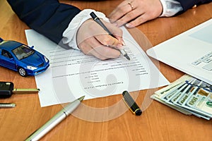 Male`s hands signing on car contract claim form and calculator, dollar, car