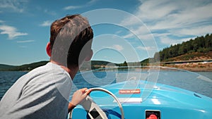 Male sailing on electric boat along mountain lake.Cheerful man floating on yacht