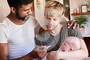 Male Same Sex Couple Checking Baby Daughters Temperature In Bathroom At Home