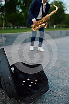 Male saxophonist plays melody in park, talent