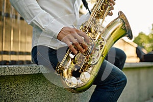 Male saxophonist plays the saxophone in park