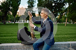 Male saxophonist takes the saxophone from the case