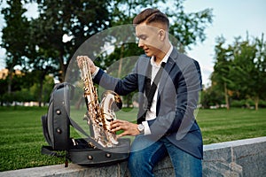 Male saxophonist takes the saxophone from the case