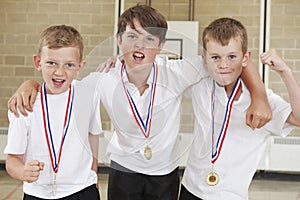 Male School Sports Team In Gym With Medals