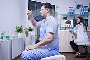 Male scientis holding a sample of green solution in a research lab