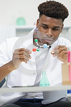 male scientist holding molecular model in lab