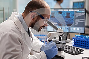 Male scientist looking under microscope at virus sample