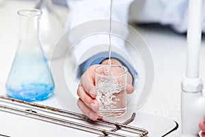 Male scientist pouring liquid into a becher photo