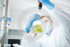 Male scientist taking probe of green liquid