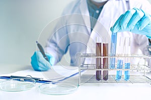 Male scientist worker in white coat working with test tubes in l