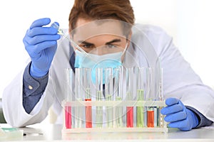 Male scientist working in laboratory, focus on rack with test tubes.