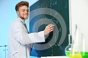 Male scientist writing chemical formula on chalkboard
