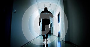 Male Security Guard Holding Flashlight Standing In Corridor