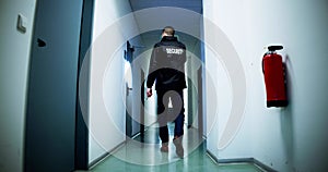 Male Security Guard Holding Flashlight Standing In Corridor