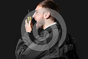 Male security guard with portable radio transmitter on dark background