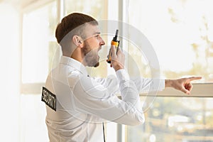 Male security guard with portable radio transmitter indoors