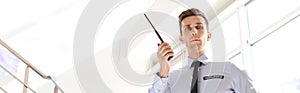 Male security guard with portable radio transmitter indoors. Banner design