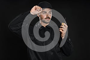 Male security guard in uniform using portable radio transmitter on background